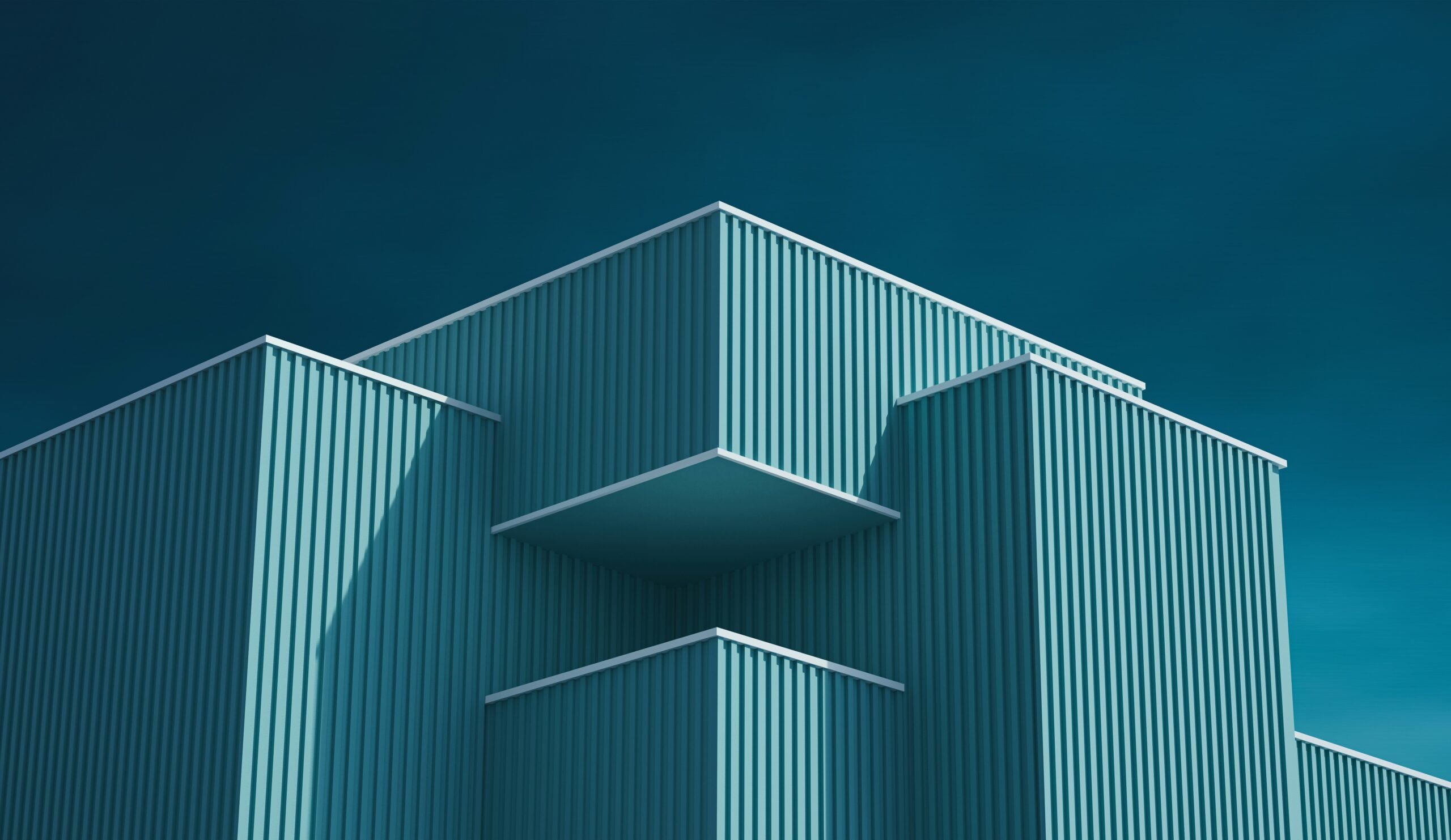 Teal modern building facade against a deep blue sky